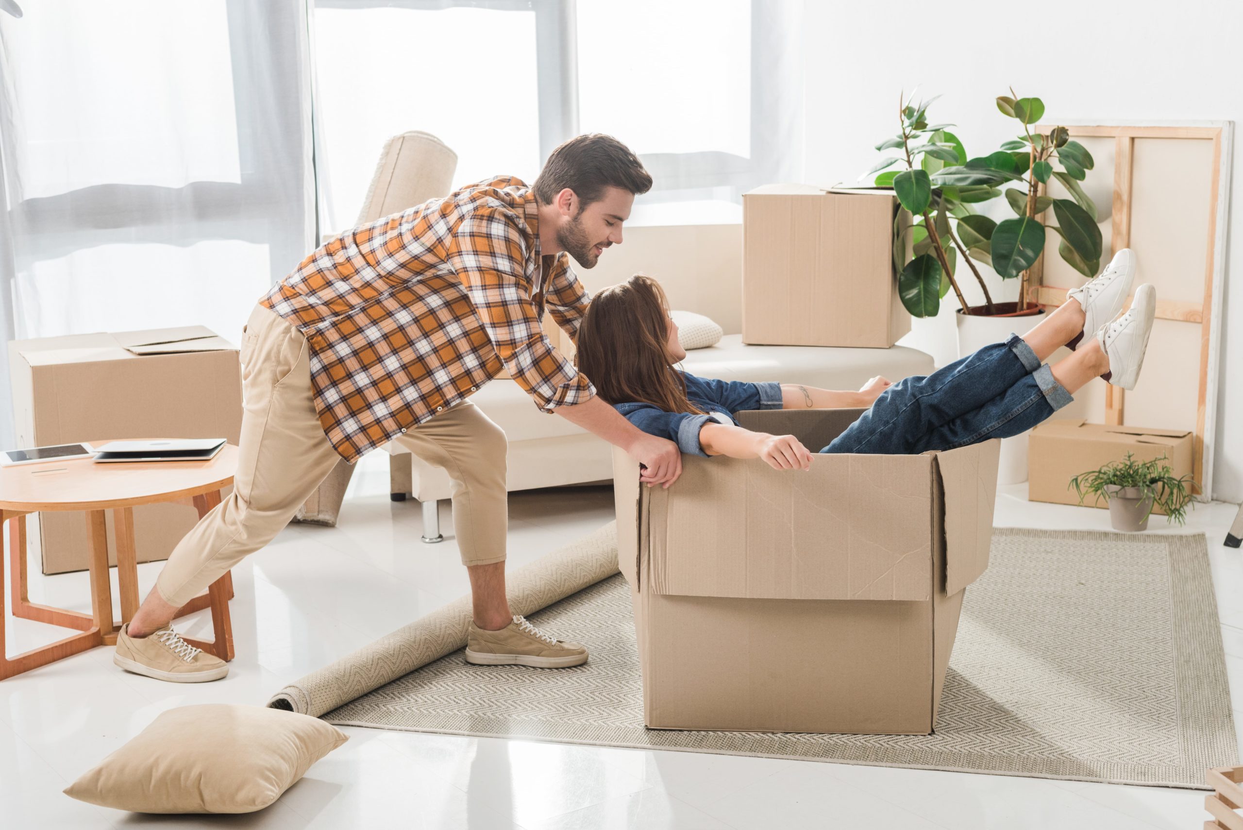 Sideview of couple having fun in new home while unpacking